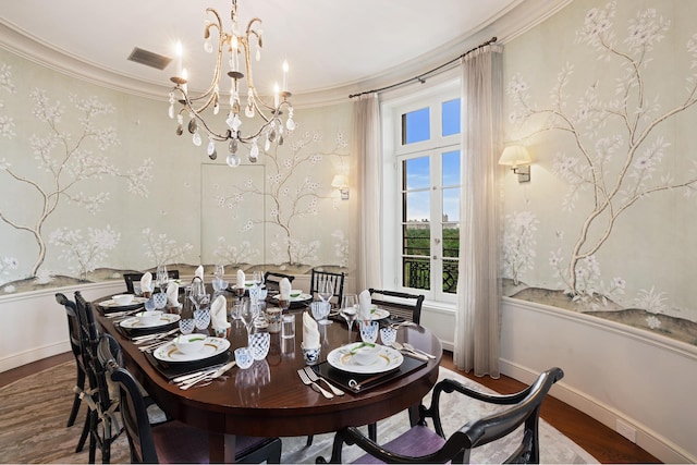 dining area with hardwood / wood-style flooring, a notable chandelier, and crown molding