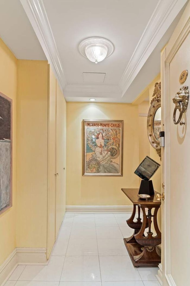 hall with crown molding, light tile flooring, and a tray ceiling