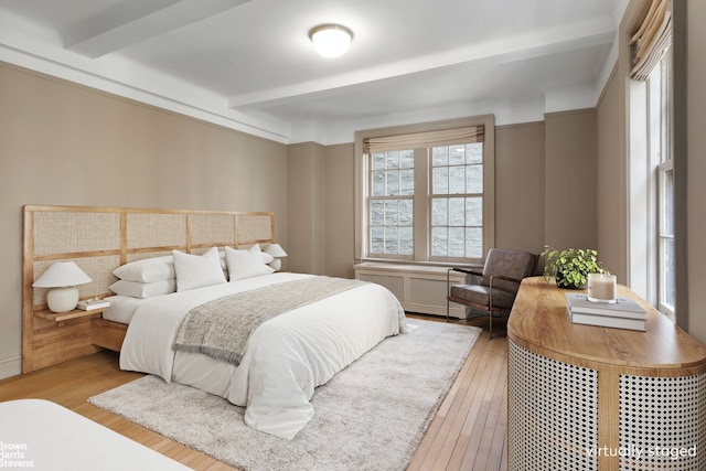 bedroom featuring beam ceiling and light wood-type flooring