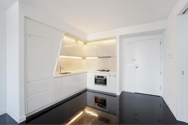 kitchen with dark wood-type flooring, stainless steel oven, and white cabinets