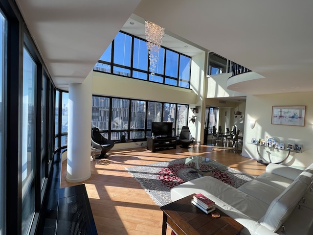 living room featuring expansive windows, wood-type flooring, a chandelier, and a high ceiling