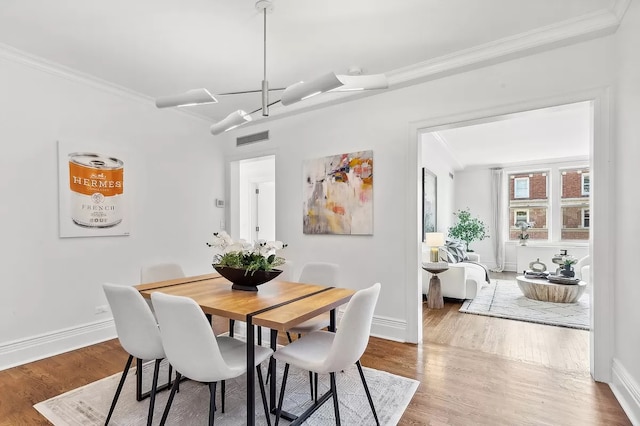 dining space featuring wood-type flooring and ornamental molding