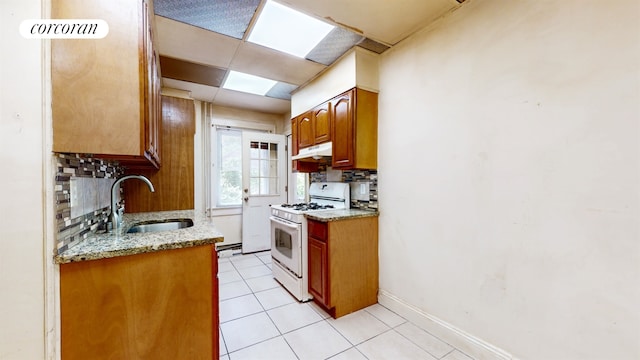 kitchen featuring white gas range oven, sink, tasteful backsplash, and light stone countertops