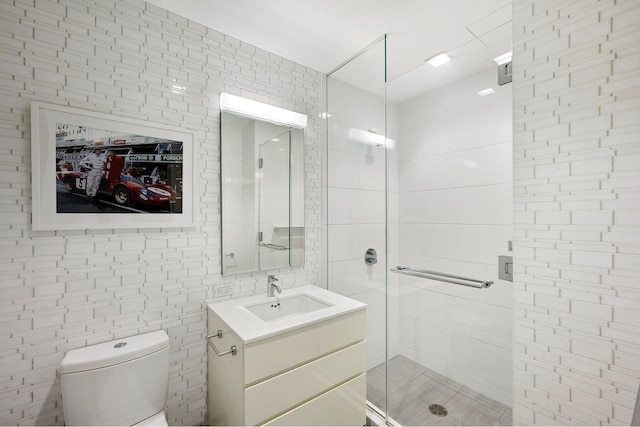 bathroom with tile walls, an enclosed shower, vanity, and toilet