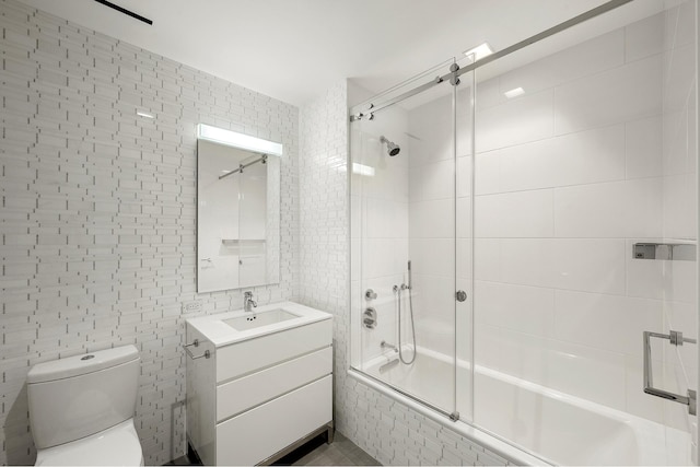 full bathroom with enclosed tub / shower combo, tile walls, vanity, and toilet