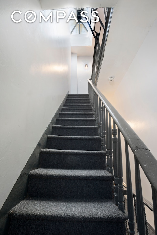 staircase featuring ceiling fan and a towering ceiling