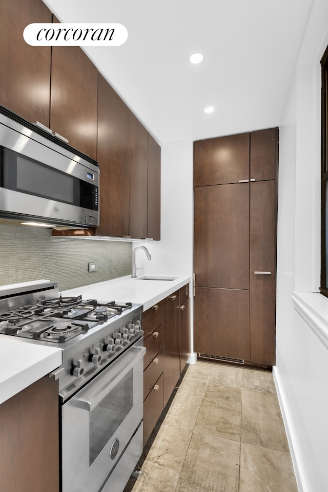 kitchen featuring tasteful backsplash, sink, dark brown cabinets, and appliances with stainless steel finishes