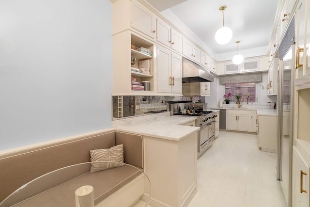 kitchen featuring white cabinetry, tasteful backsplash, high end range, decorative light fixtures, and light stone counters