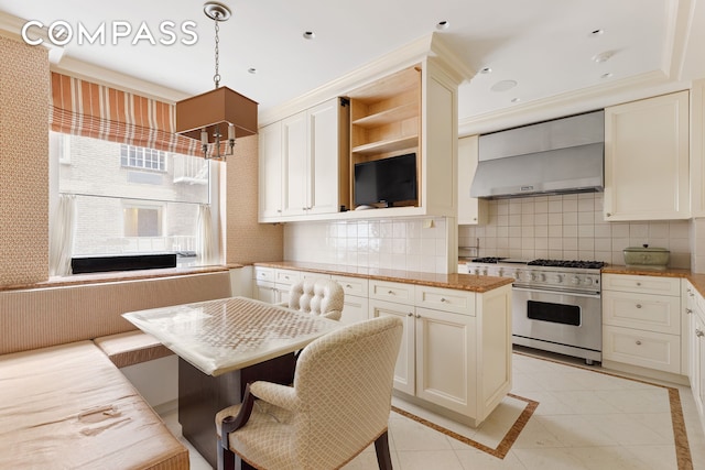 kitchen featuring light tile floors, backsplash, stainless steel range, wall chimney range hood, and decorative light fixtures