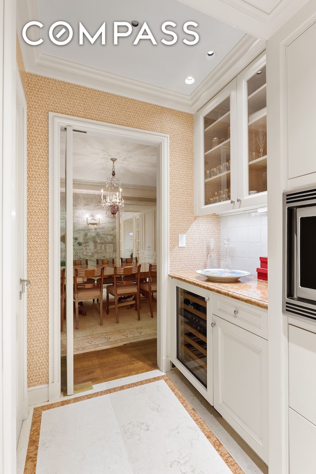 kitchen featuring an inviting chandelier, backsplash, beverage cooler, light hardwood / wood-style flooring, and white cabinets