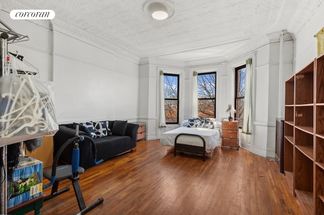 bedroom with a textured ceiling, wood-type flooring, and ornamental molding