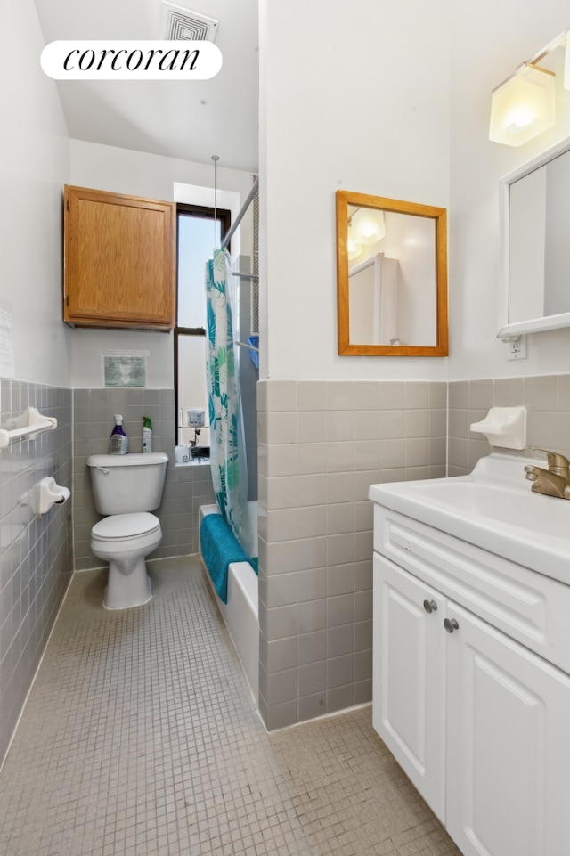 full bathroom featuring shower / bathtub combination with curtain, toilet, tile patterned floors, and tile walls