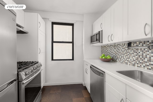 kitchen featuring appliances with stainless steel finishes, tasteful backsplash, white cabinets, and dark tile floors