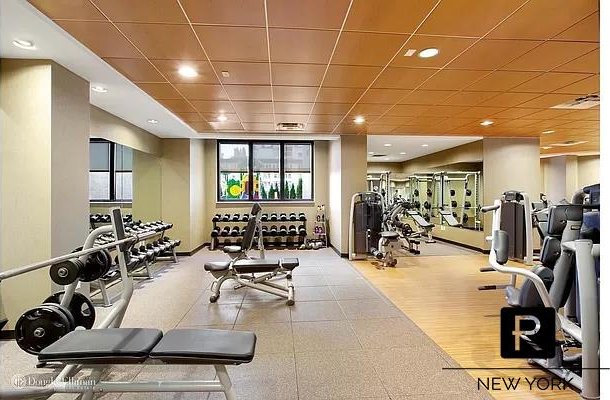 workout area with a drop ceiling and light wood-type flooring