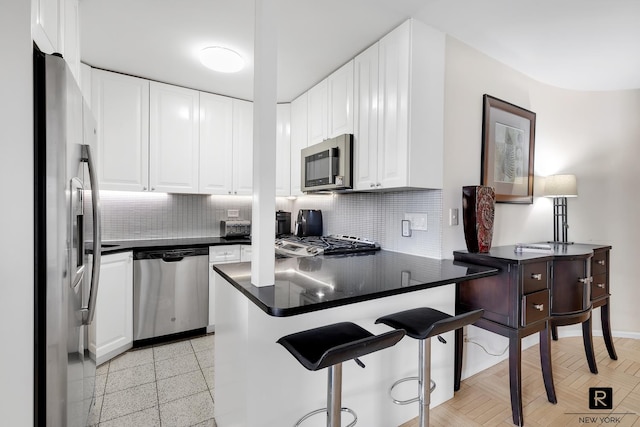 kitchen with kitchen peninsula, white cabinetry, backsplash, and appliances with stainless steel finishes