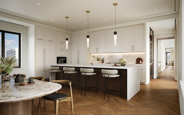 kitchen with decorative light fixtures, dark parquet flooring, ornamental molding, and an island with sink