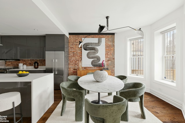 interior space with dark wood-type flooring, built in refrigerator, a center island, pendant lighting, and a kitchen breakfast bar