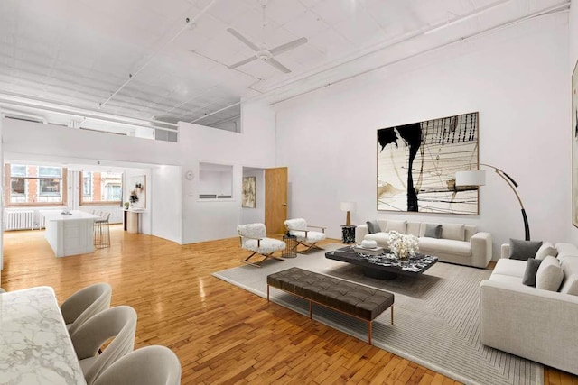 living room featuring ceiling fan, radiator heating unit, and light hardwood / wood-style flooring