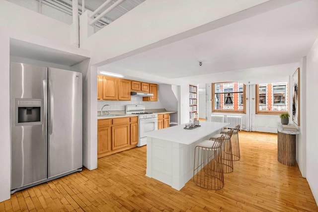 kitchen with a center island, sink, decorative backsplash, stainless steel fridge, and white gas range