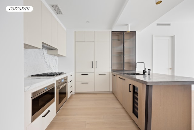 kitchen featuring tasteful backsplash, white cabinets, light hardwood / wood-style floors, and appliances with stainless steel finishes