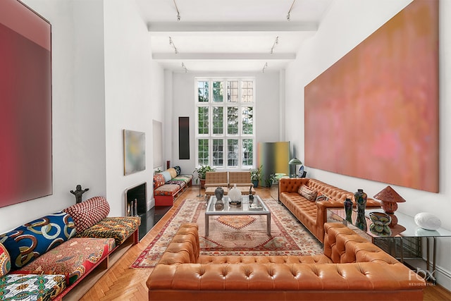 living room featuring a towering ceiling, beam ceiling, track lighting, and parquet flooring