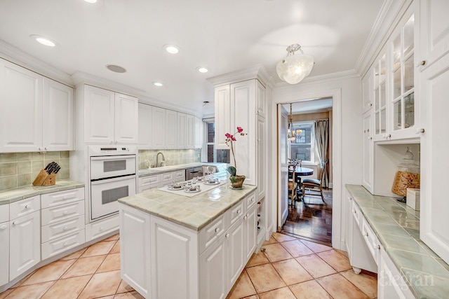 kitchen featuring white cabinetry, tile countertops, light tile patterned floors, and white appliances