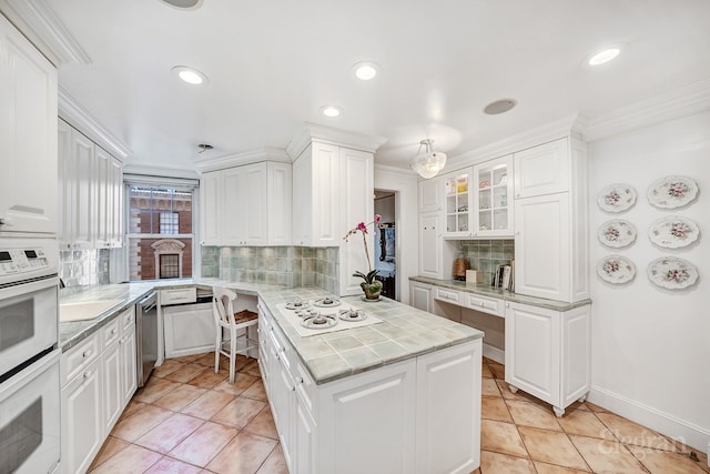 kitchen featuring white cabinetry, crown molding, decorative backsplash, and white appliances