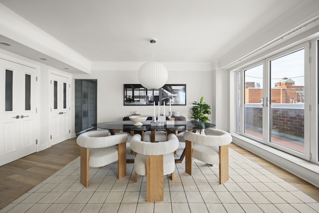 dining area with light wood-type flooring and ornamental molding