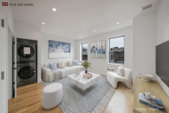 living room with stacked washer / dryer and light hardwood / wood-style floors