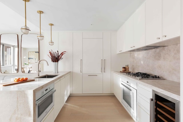 kitchen featuring beverage cooler, white cabinetry, sink, pendant lighting, and stainless steel appliances