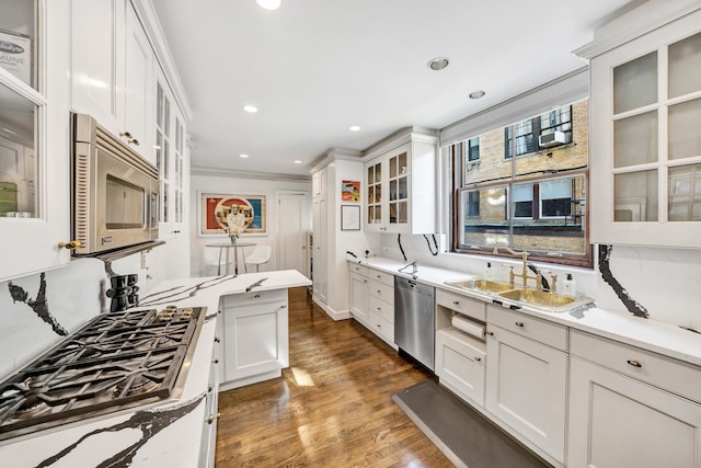 kitchen with light stone counters, white cabinets, stainless steel appliances, crown molding, and dark hardwood / wood-style flooring