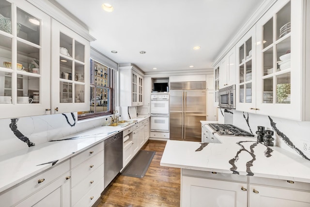 kitchen featuring built in appliances, light stone countertops, dark hardwood / wood-style flooring, and white cabinetry