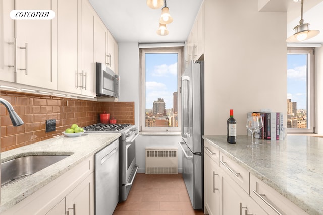 kitchen with white cabinetry, radiator heating unit, light stone counters, decorative backsplash, and high end appliances