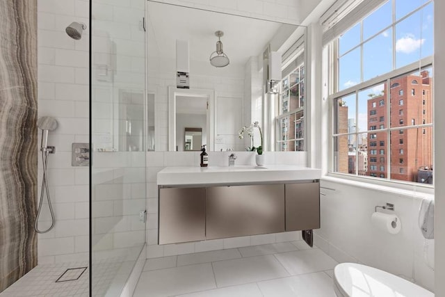 bathroom with tile patterned floors, vanity, toilet, and a shower with door