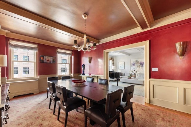 dining room featuring beamed ceiling, a notable chandelier, crown molding, and light hardwood / wood-style flooring