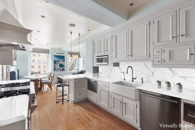 kitchen featuring a kitchen breakfast bar, sink, hardwood / wood-style flooring, appliances with stainless steel finishes, and decorative light fixtures