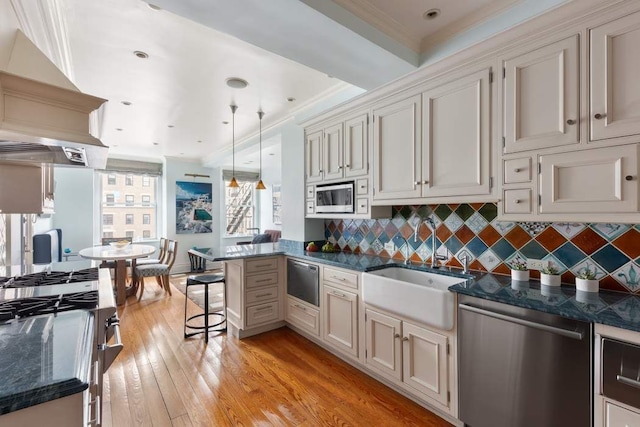 kitchen featuring pendant lighting, crown molding, light hardwood / wood-style flooring, appliances with stainless steel finishes, and a breakfast bar area