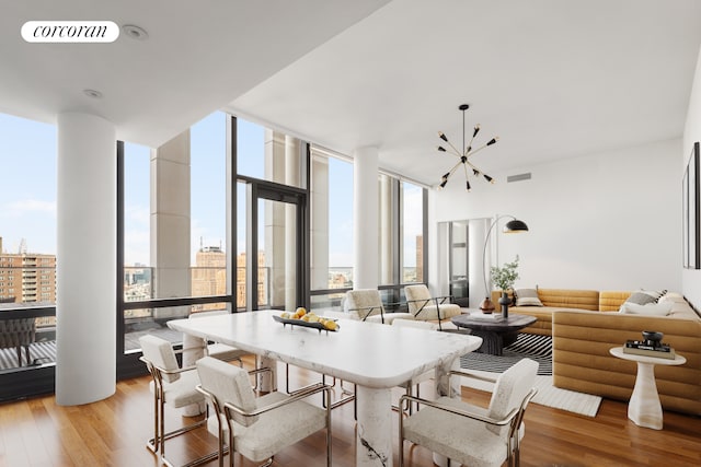 dining room featuring floor to ceiling windows, a chandelier, and light hardwood / wood-style flooring