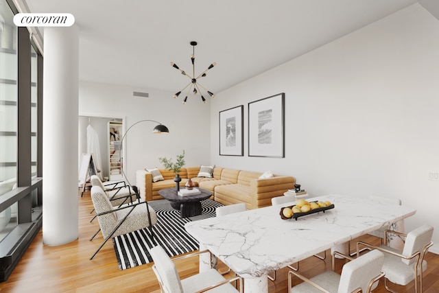 dining space with light hardwood / wood-style floors and a notable chandelier