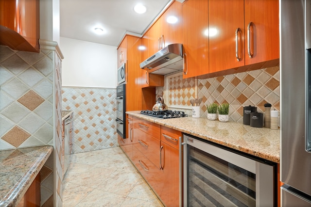 kitchen featuring appliances with stainless steel finishes, beverage cooler, tasteful backsplash, light stone counters, and light tile floors