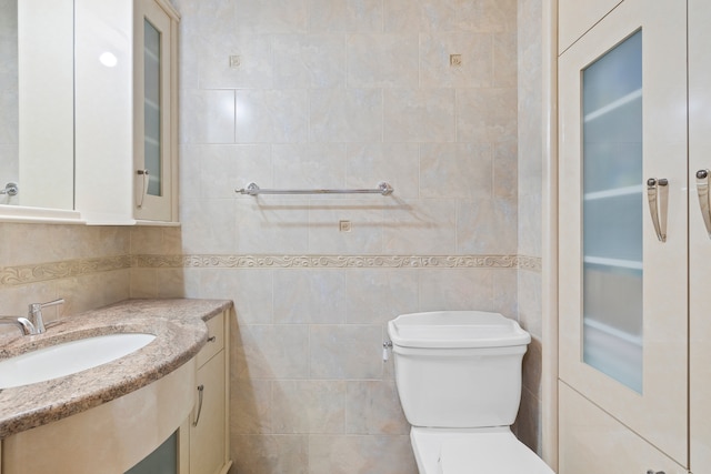 bathroom featuring tile walls, oversized vanity, and toilet