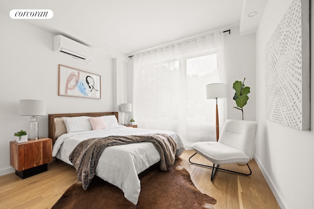 bedroom with a wall mounted air conditioner and light wood-type flooring