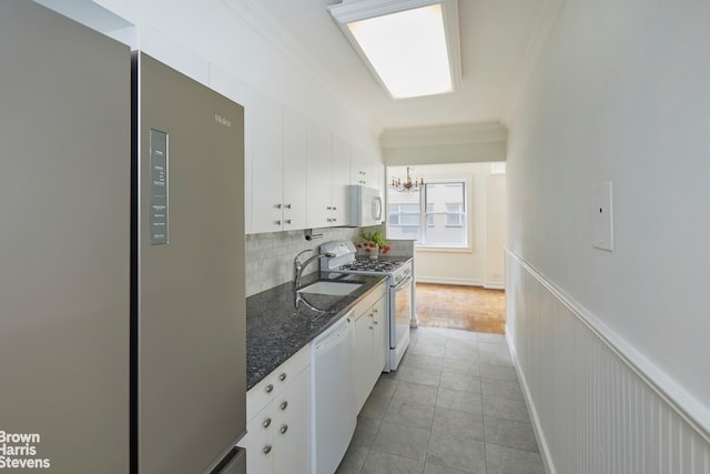 kitchen with tile flooring, crown molding, tasteful backsplash, white appliances, and white cabinetry