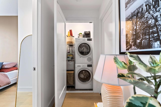 clothes washing area featuring stacked washer and clothes dryer and light wood-type flooring