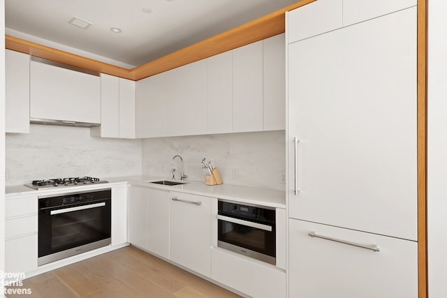 kitchen featuring oven, gas cooktop, white cabinetry, and tasteful backsplash