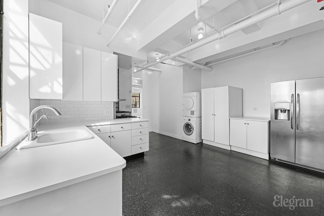 kitchen featuring white cabinetry, sink, tasteful backsplash, stacked washer and clothes dryer, and appliances with stainless steel finishes