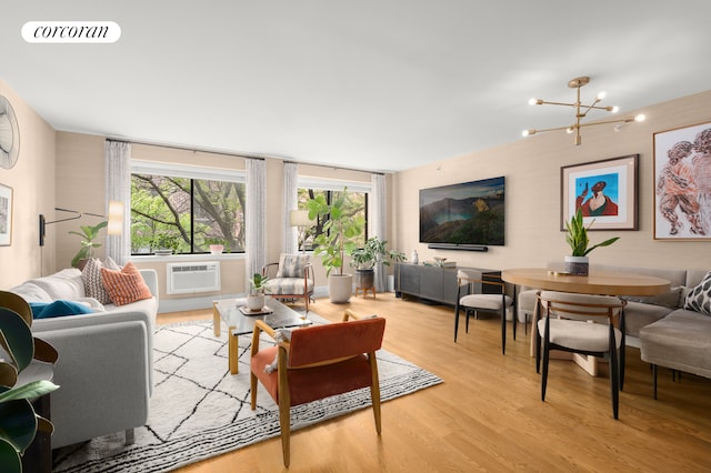 living room featuring light hardwood / wood-style floors, a wall mounted AC, and an inviting chandelier