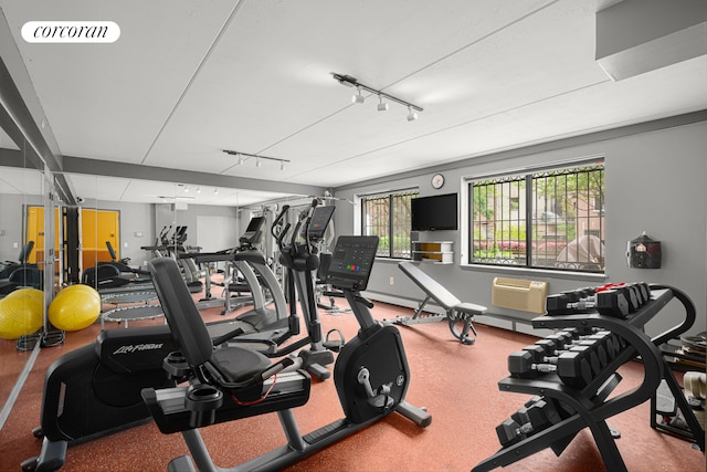 exercise room with an AC wall unit and rail lighting