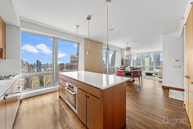 kitchen with decorative light fixtures, gas cooktop, hardwood / wood-style floors, and a kitchen island