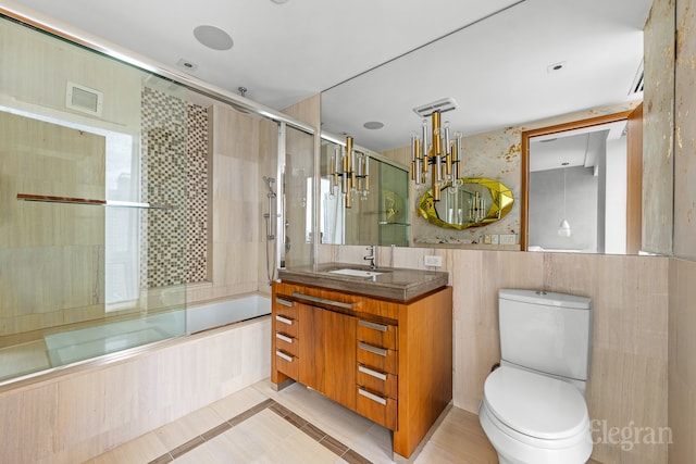 full bathroom with shower / bath combination with glass door, tile floors, toilet, tile walls, and oversized vanity